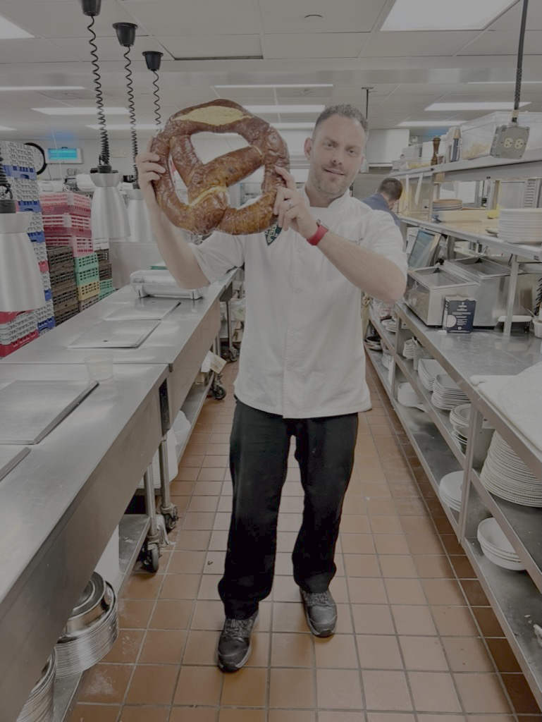 Jeremy Leinen holding a giant soft pretzel in a commercial kitchen