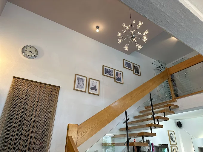 Salon E Treppenhaus mit Kronleuchter und Schwarzweißfotos