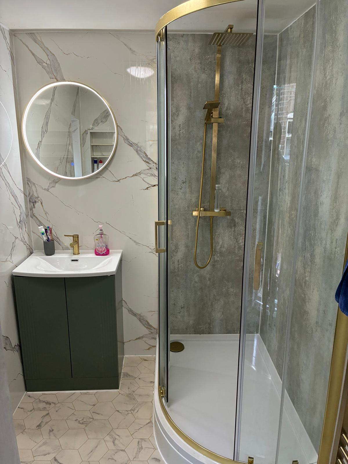 Master ensuite with LED-lit circular mirror and gold fixtures