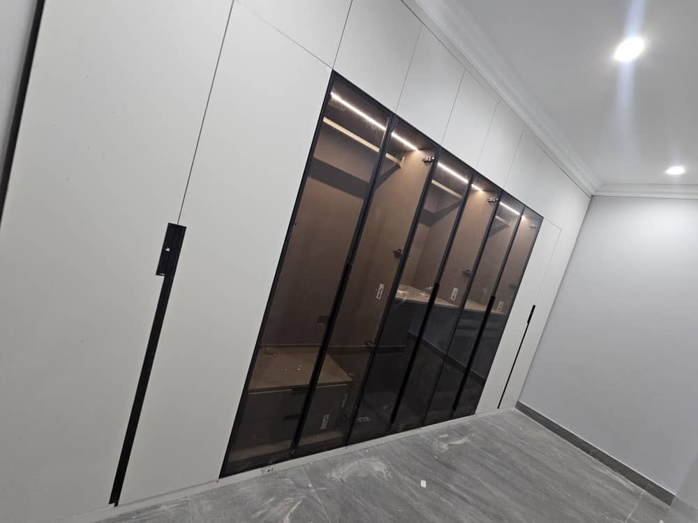 Fitted wardrobe with black-framed glass doors and internal LED lighting