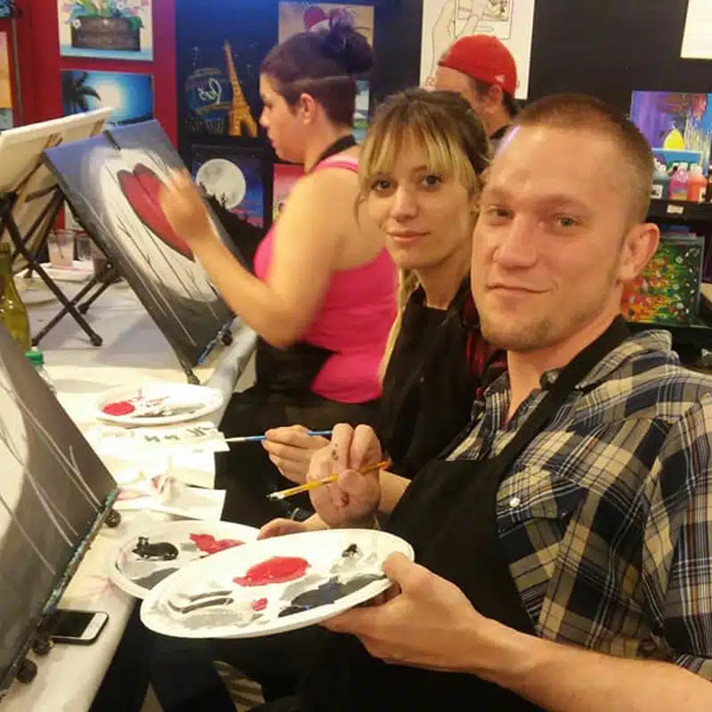 Couple painting together at a Wine & Canvas event