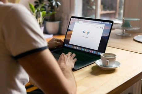 Person using Google search on a laptop with coffee