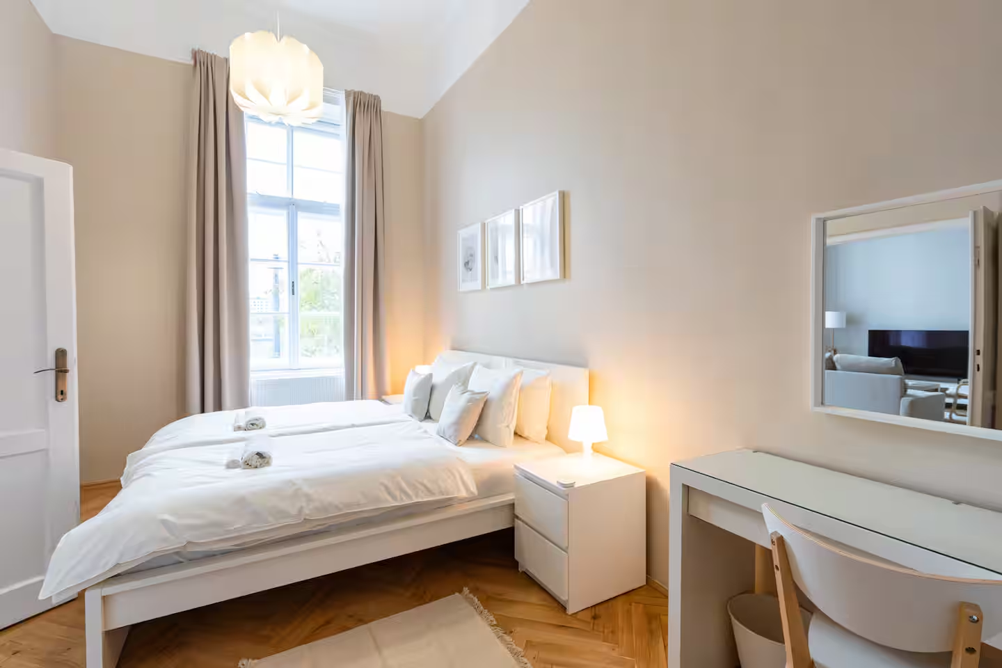 Spacious bedroom with white bed, desk area and pendant lamp