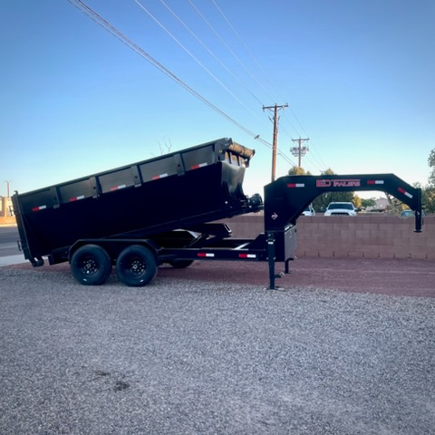 Side profile of black roll-off dumpster trailer against brick wall in Albuquerque