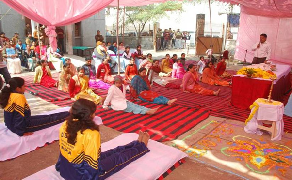 Large yoga session with pink tent and participants on mats