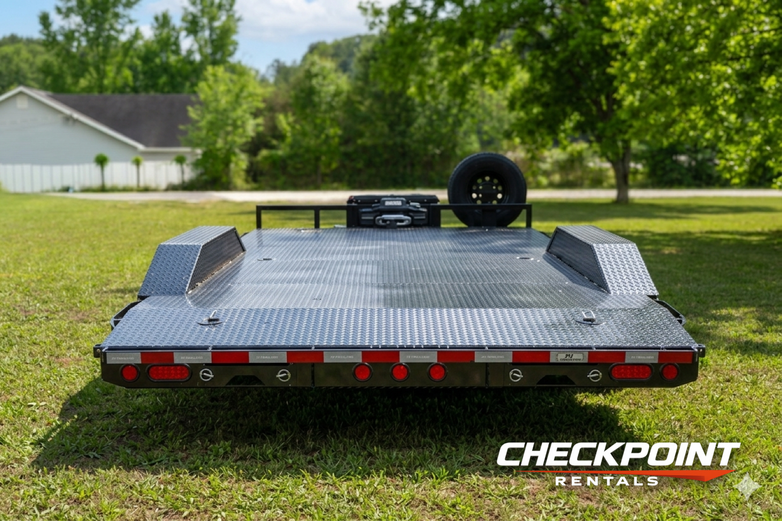 Car hauler front-on view showing diamond plate deck and spare tire