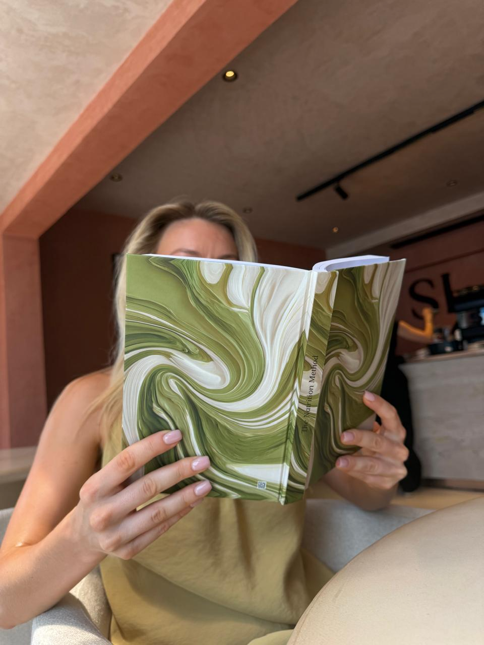 Woman reading the green marble edition of The Natrition Method journal