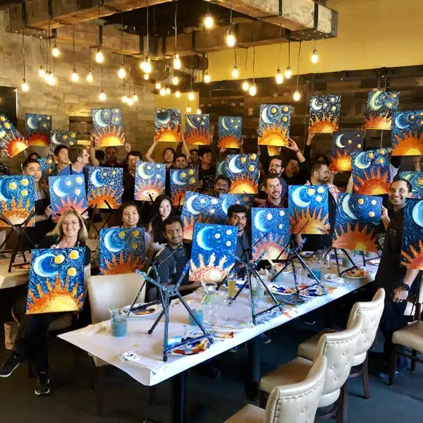 Large corporate team holding starry night sun and moon paintings
