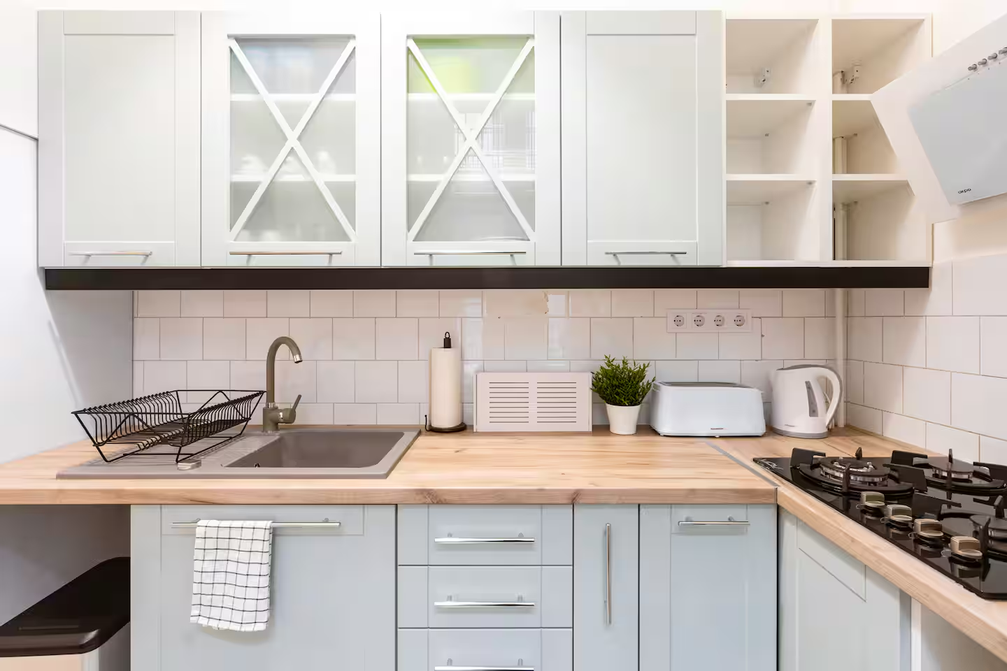 Modern kitchen with light blue cabinets, wooden countertop and gas stove