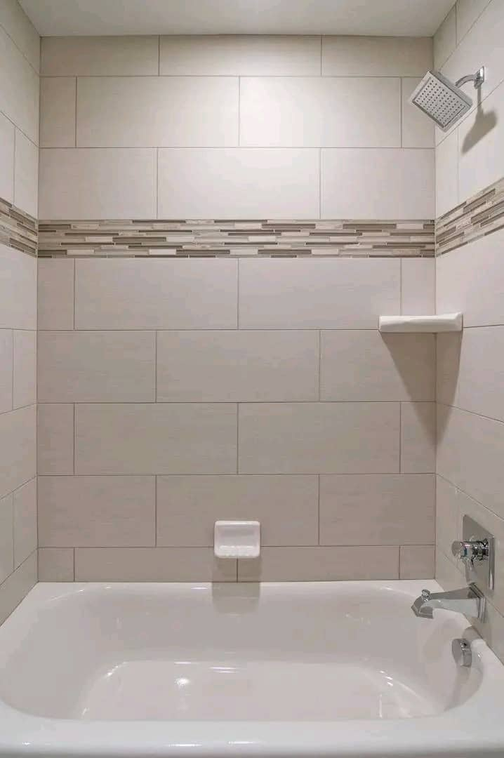 Bathroom with large beige wall tiles and decorative mosaic border