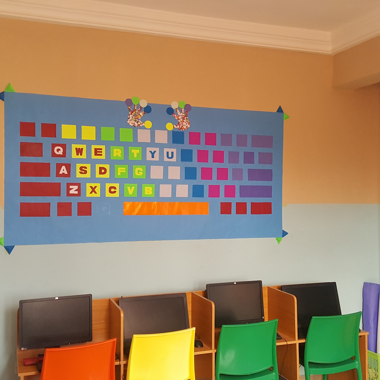 Computer lab with a colourful keyboard wall display and monitors