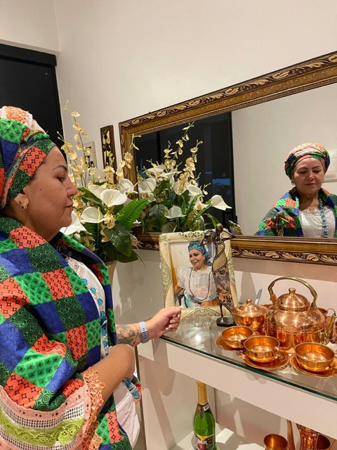 Mãe Mariana em seu altar com itens rituais de cobre e flores