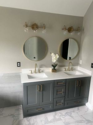 Double vanity with dark gray cabinetry, gold hardware, and round mirrors