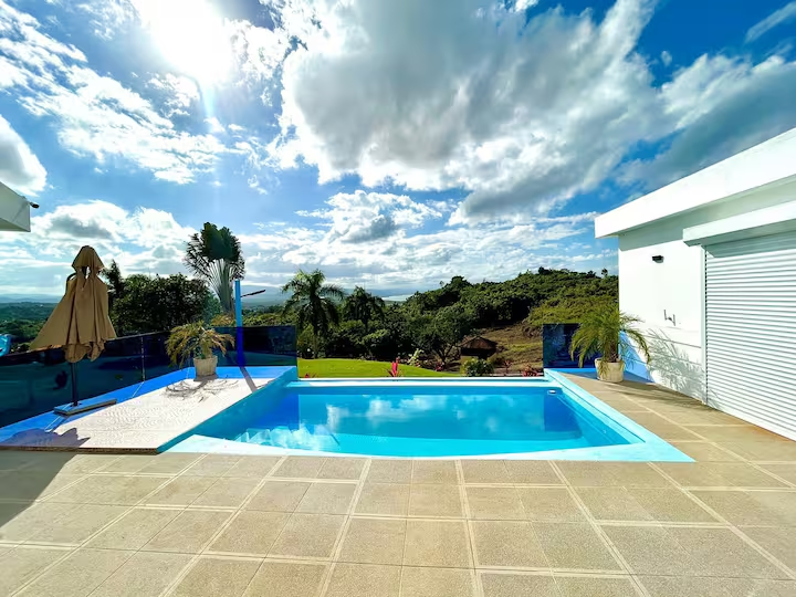 Vista diurna de la piscina con cielo azul brillante y paisaje tropical