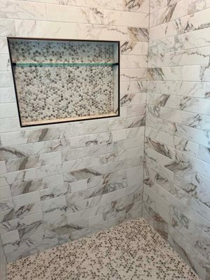 White marble shower corner with built-in mosaic niche