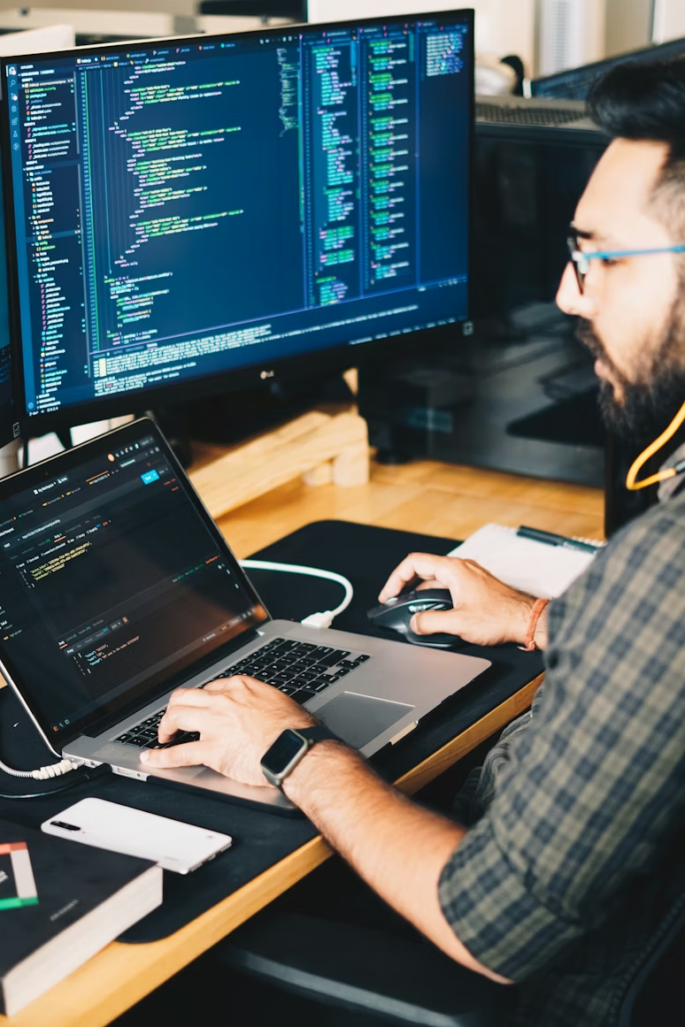 Developer working at desk with multiple monitors showing code
