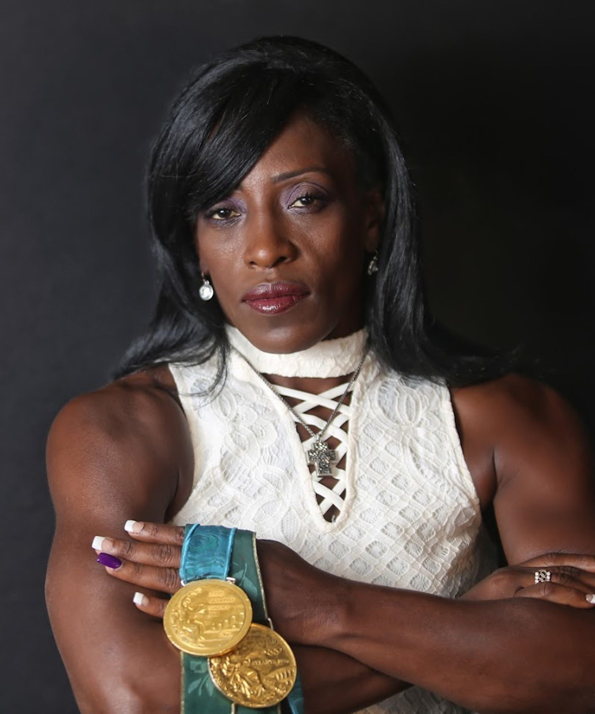 Ruthie Bolton posing with her two Olympic gold medals, arms crossed