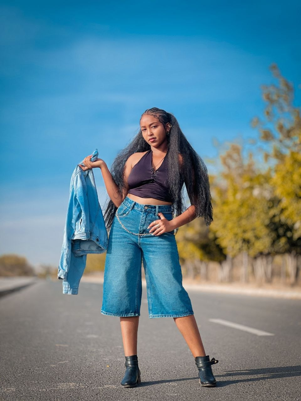 Model in a black top and denim culottes outdoors