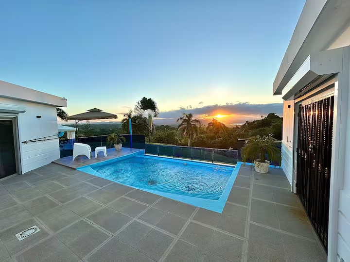 Vista de la piscina durante el atardecer con el sol poniente en el horizonte