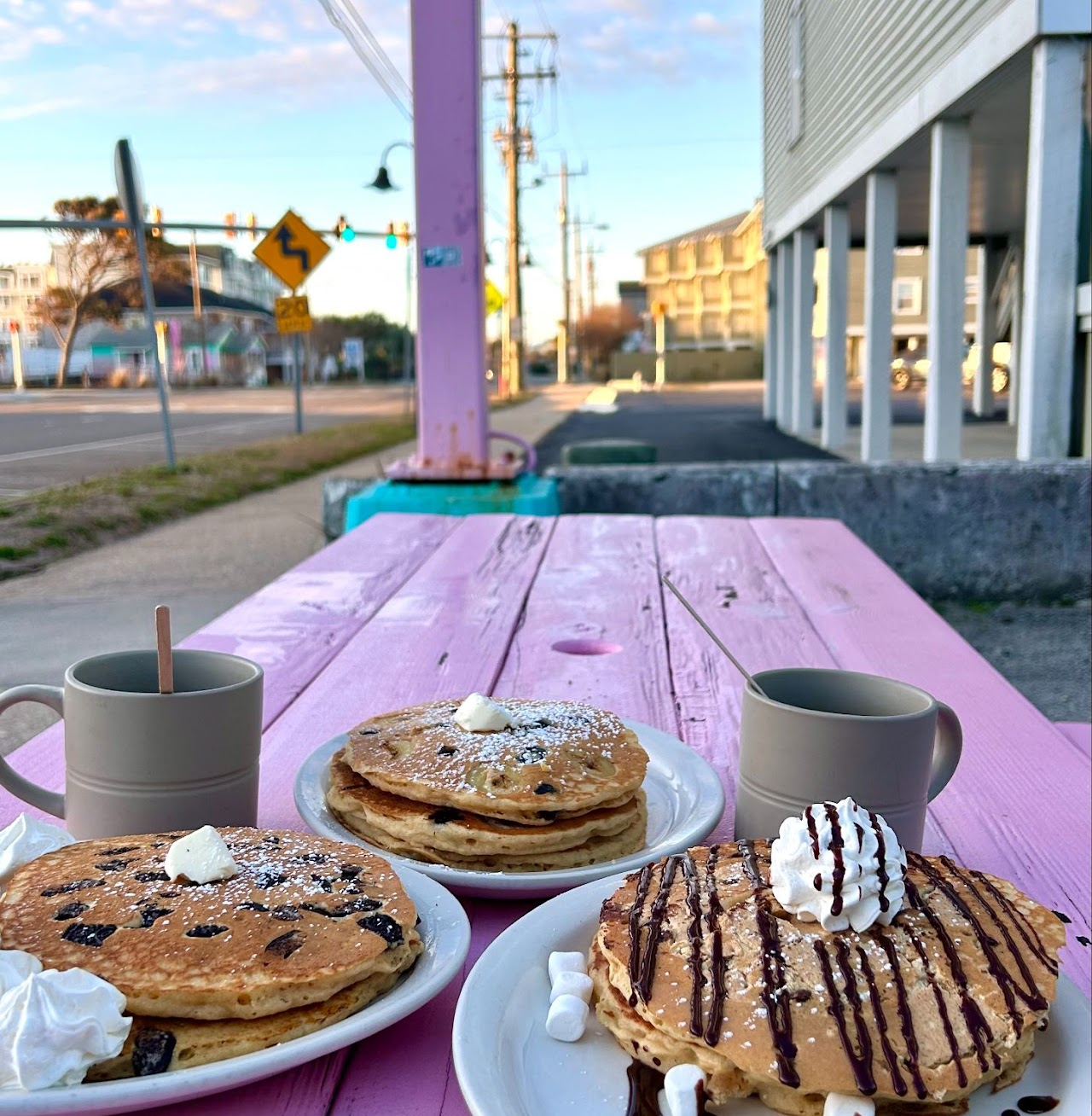 Pancakes and chocolate-drizzled French toast on a pink picnic table