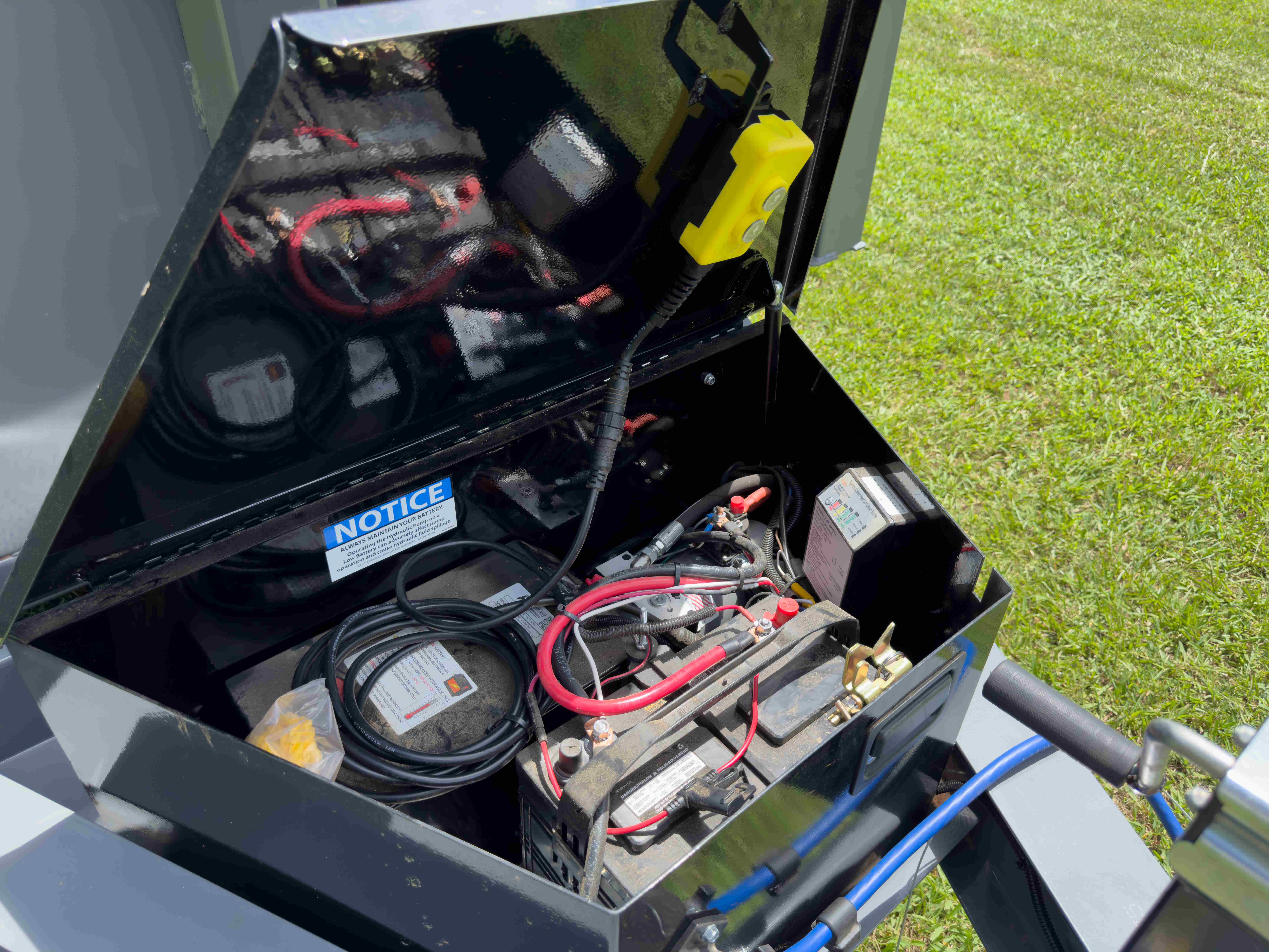Dumpster trailer hydraulic battery box open showing pump and wiring