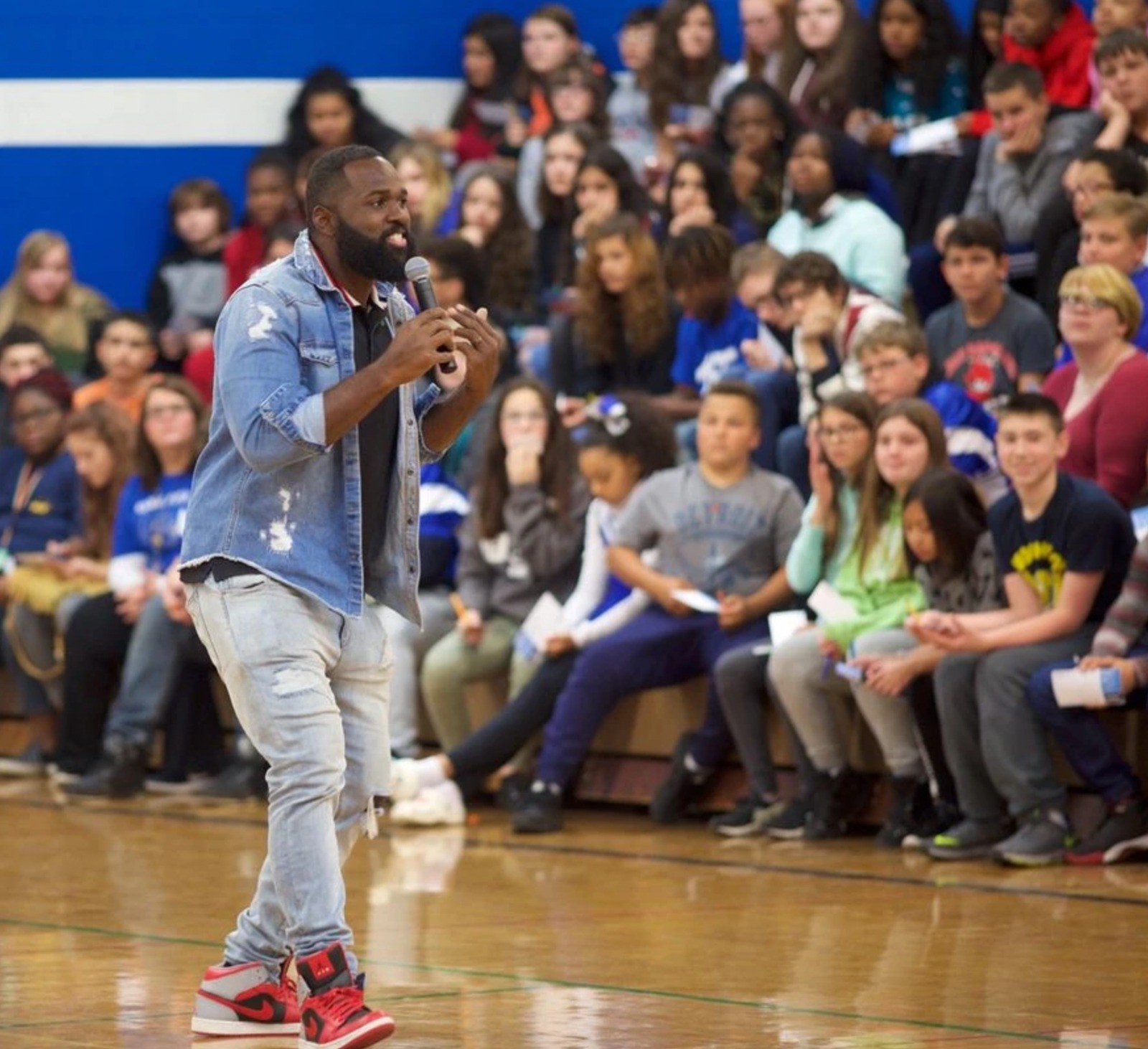 Pro athlete speaking passionately to students in gymnasium