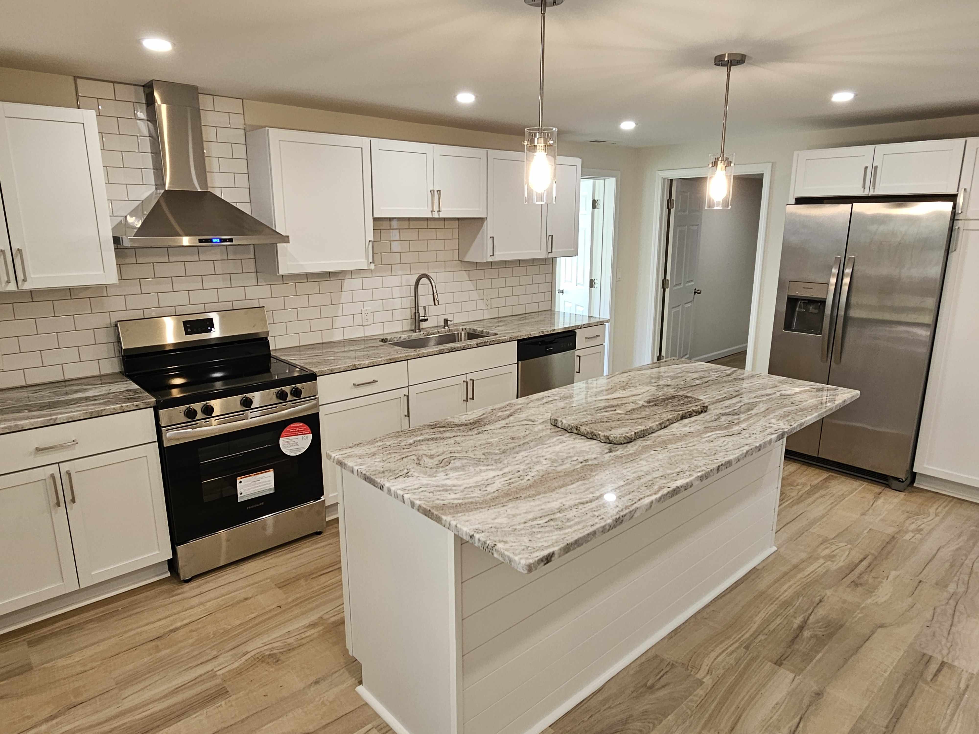 Completed kitchen remodel by MW Contracting Pros: white shaker cabinets, granite island, subway tile backsplash, and stainless steel appliances in Rochester, NY