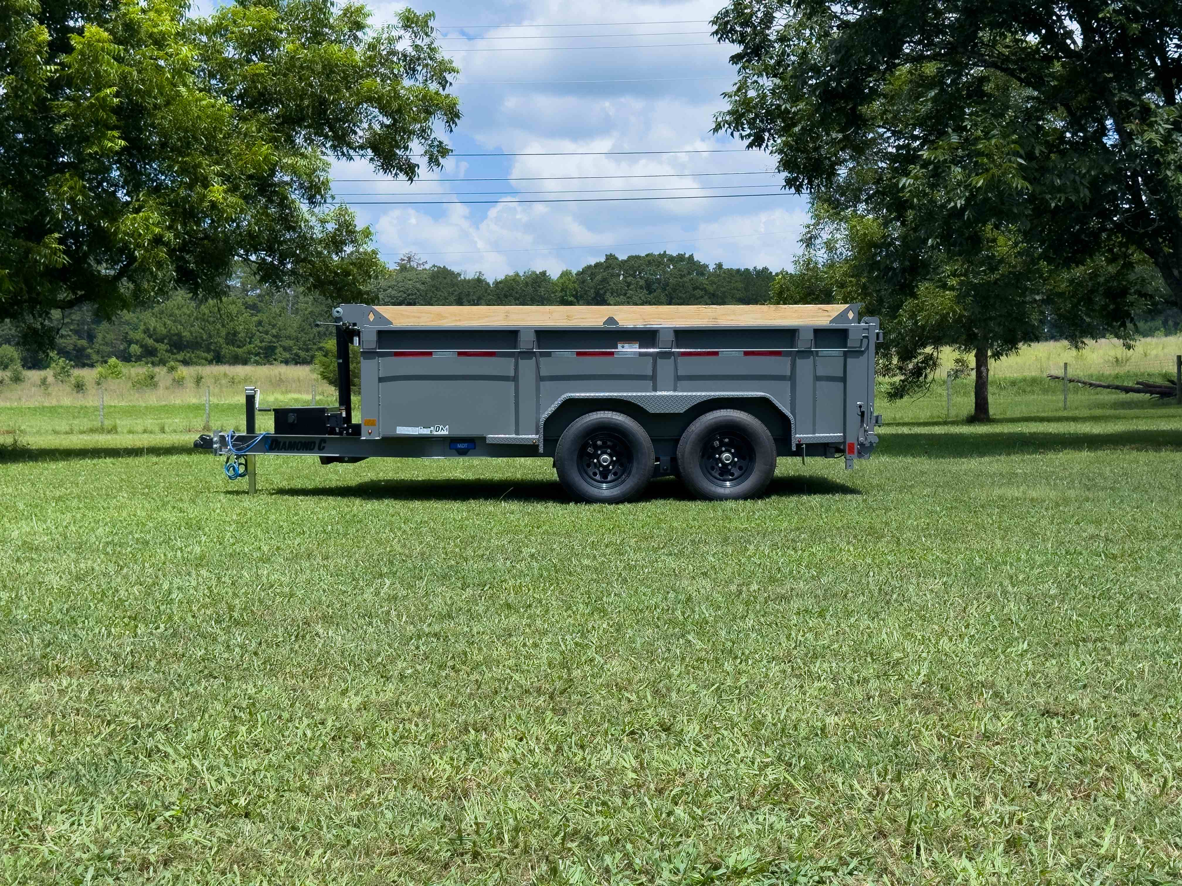 Diamond C dumpster trailer rear side profile on grass with wood-capped sides