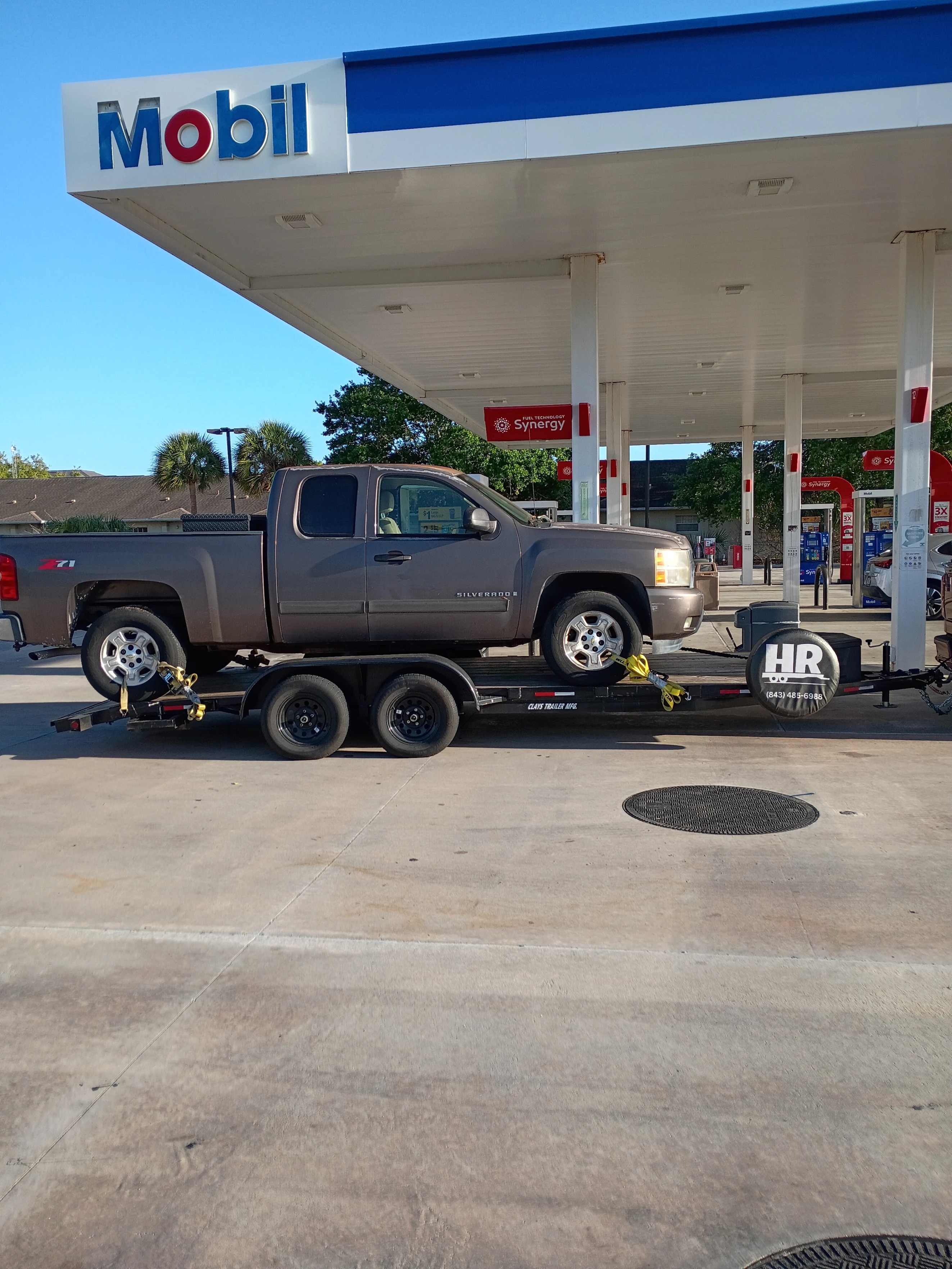 Truck towing a car hauler trailer at a gas station