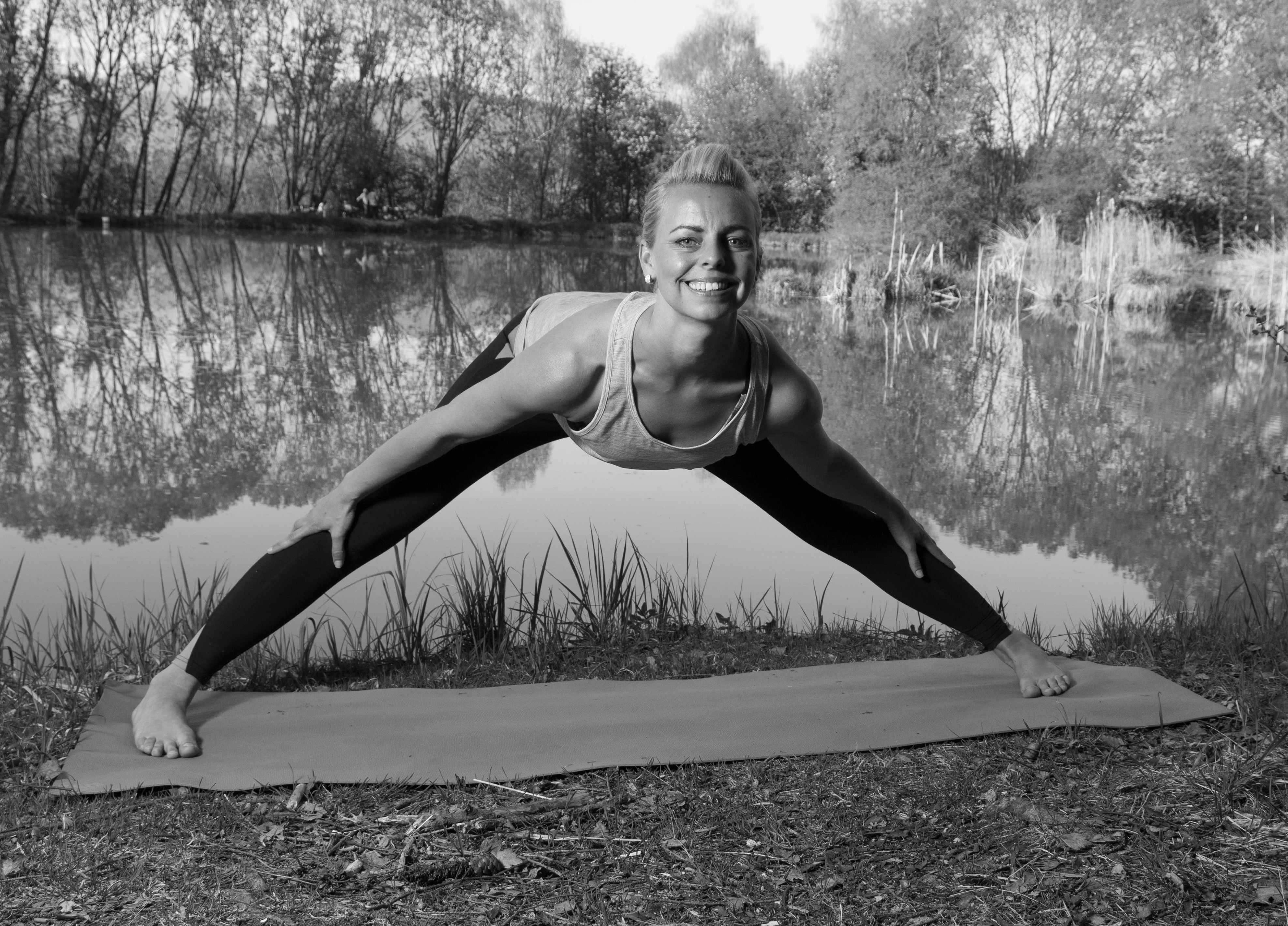 Daniela lächelnd in einer weiten Grätsche am Teich