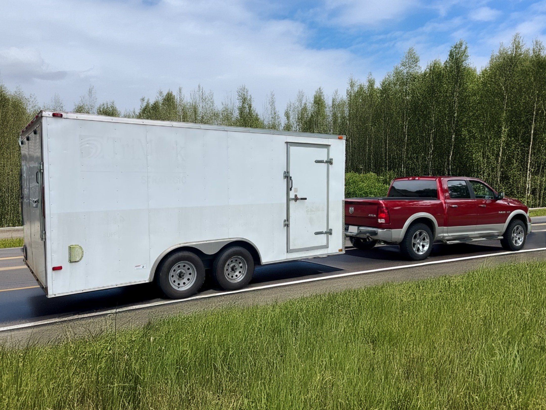 Red pickup truck towing a white enclosed trailer on a highway in Winston-Salem, NC