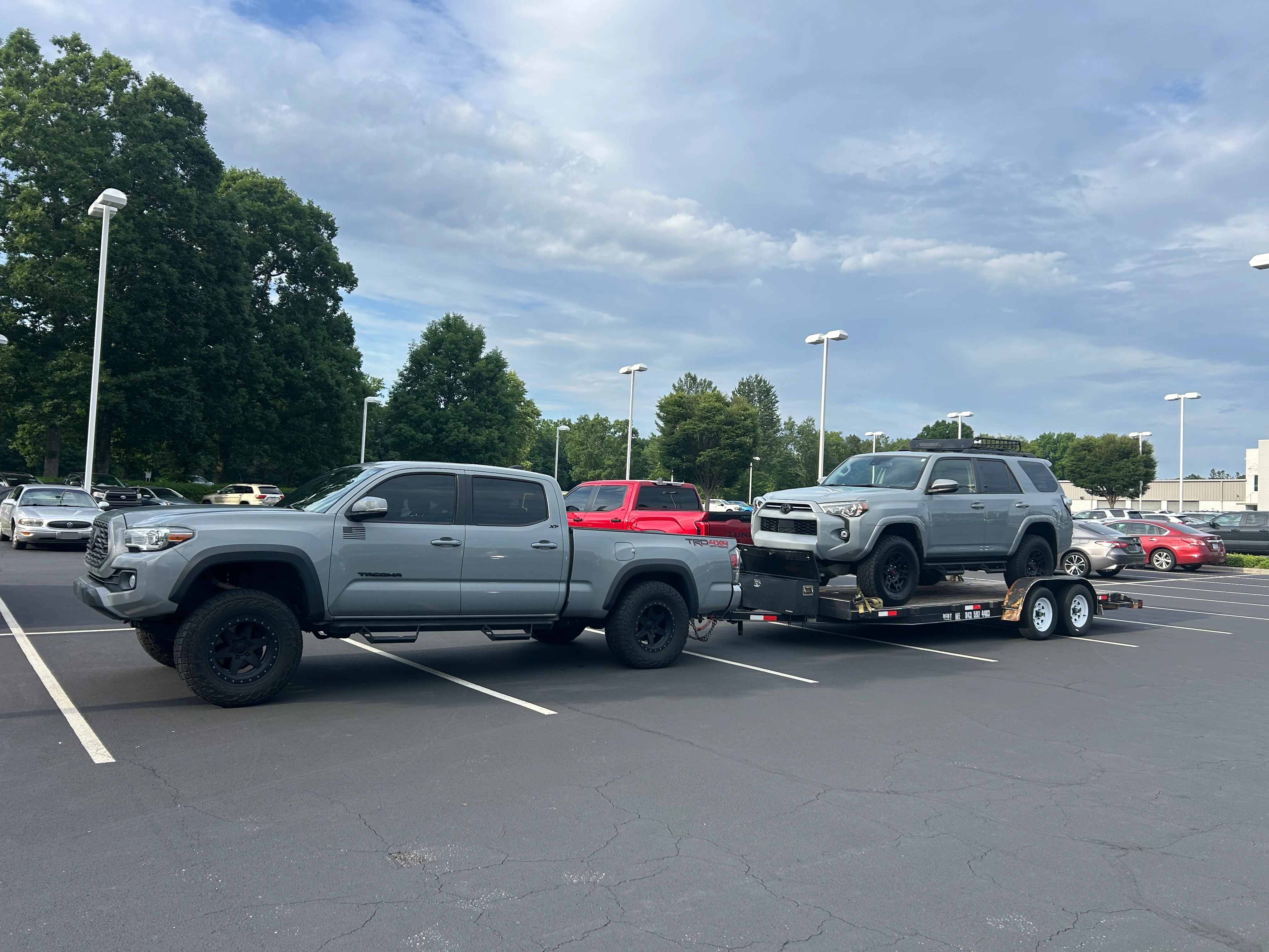 Truck towing a car hauler loaded with an SUV in a parking lot