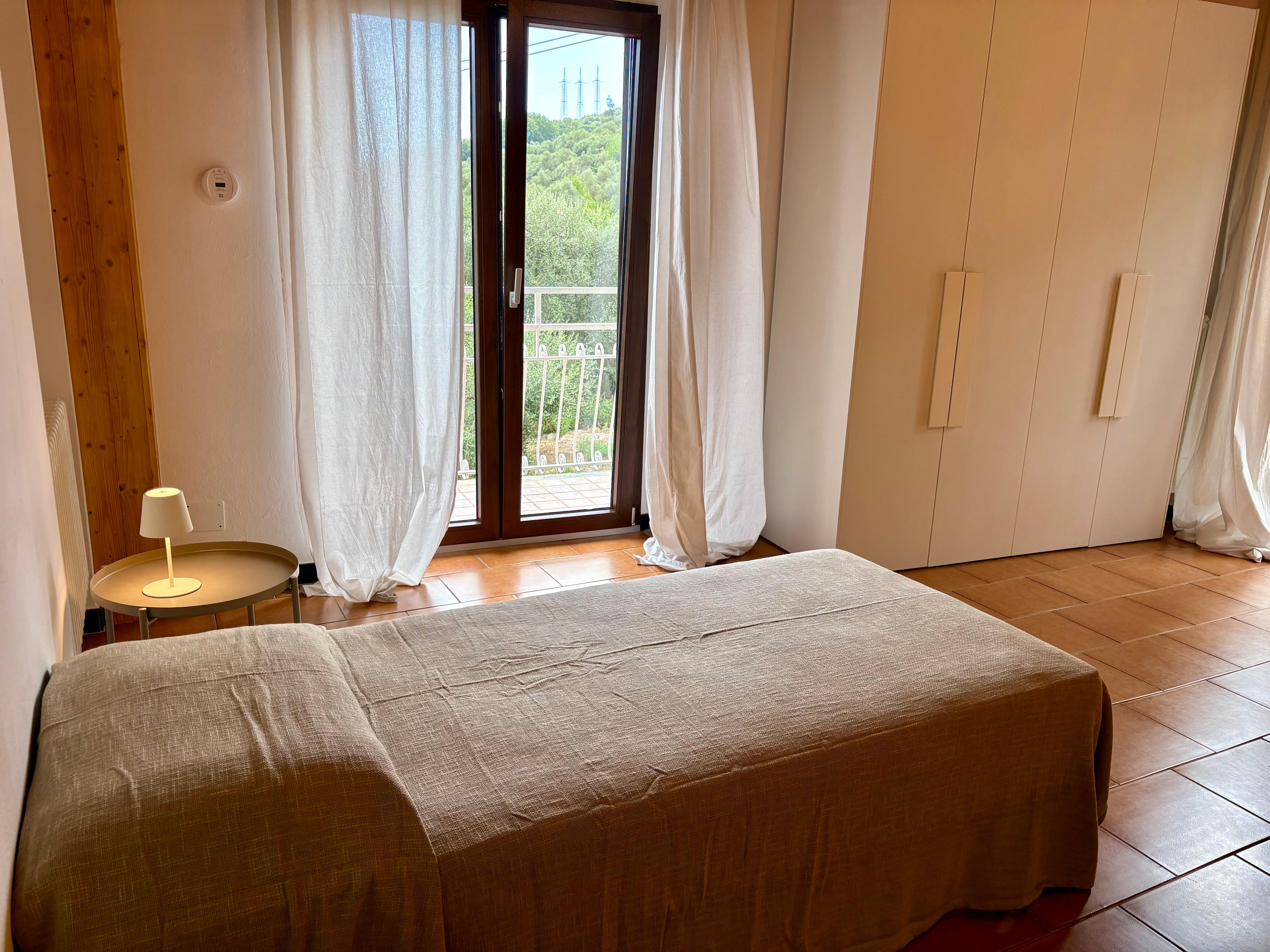 Camera matrimoniale Ca Piera vista balcone colline tende bianche Diano Borello