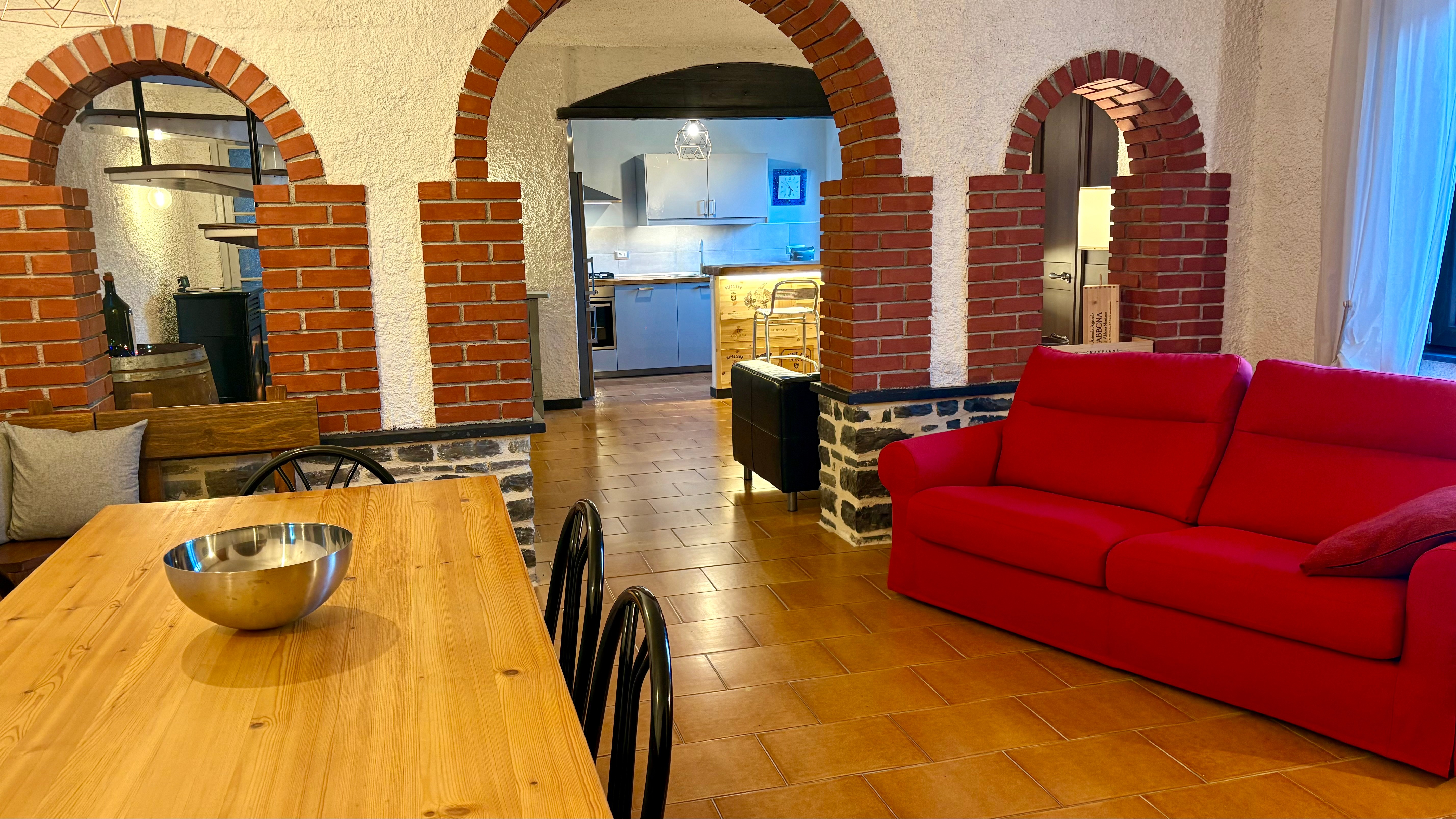 Spazio interno Ca Piera archi in mattone cucina rossa tavolo legno Diano Borello