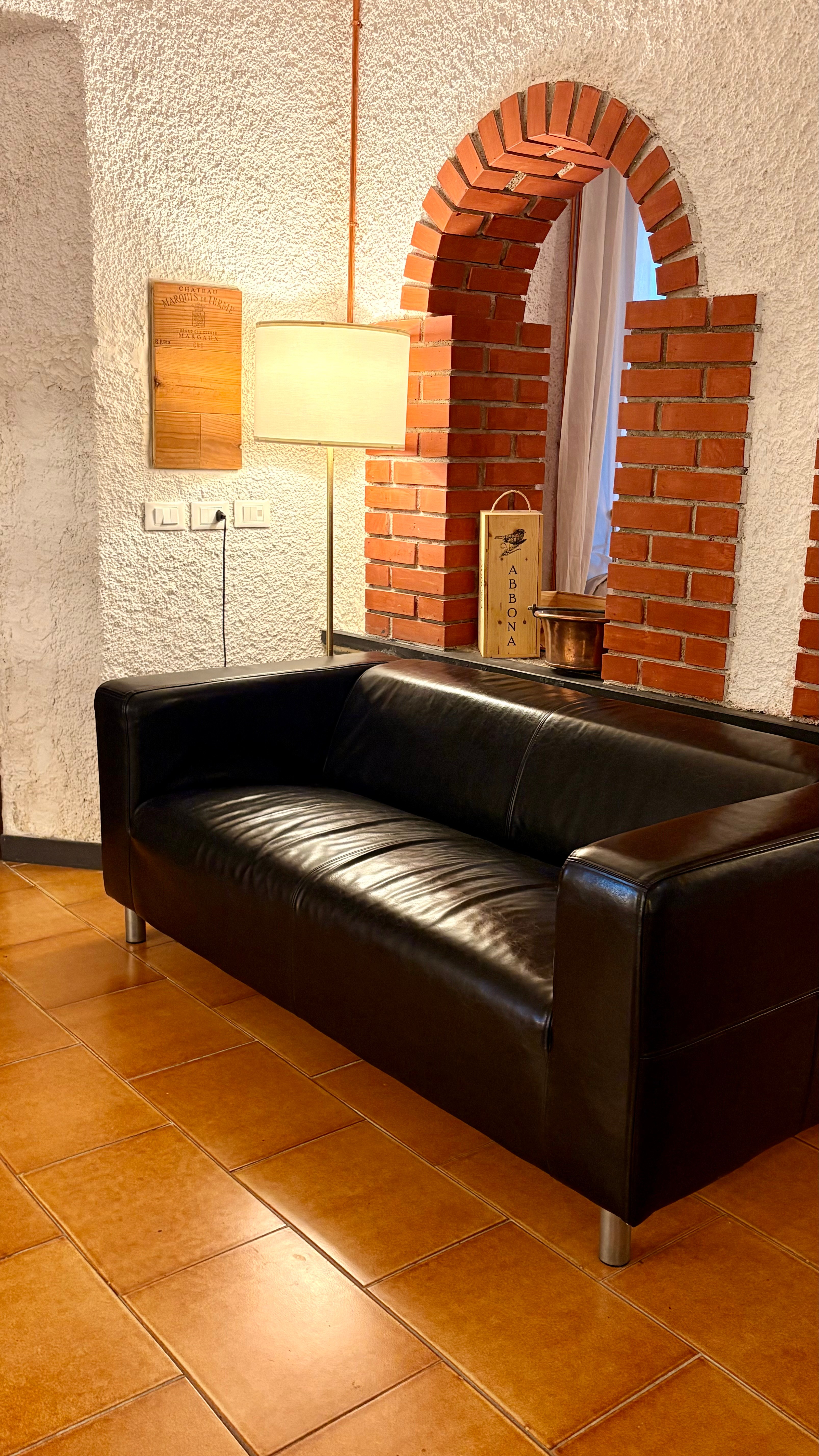 Spazio interno arco divano nero Ca Piera architettura Diano Borello