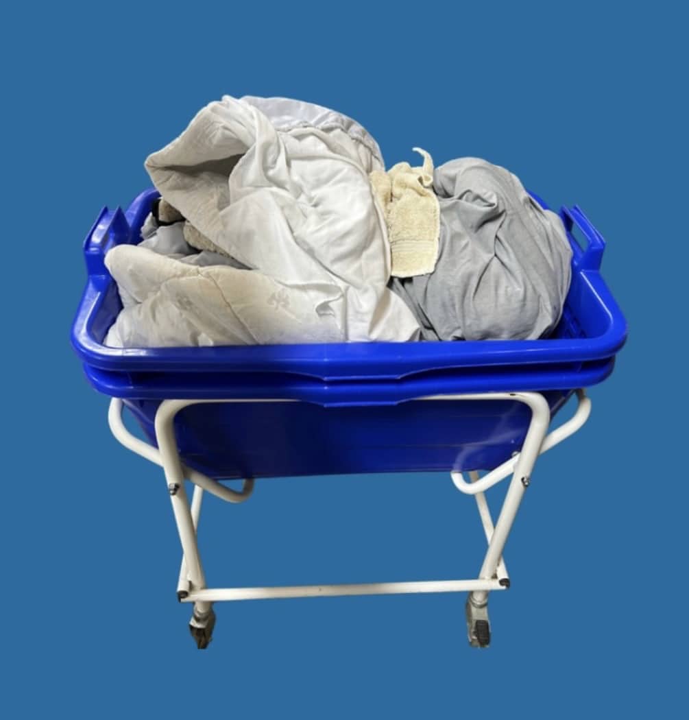 Bettdecken und Laken in einem blauen Wäschewagen bereit zur professionellen Reinigung