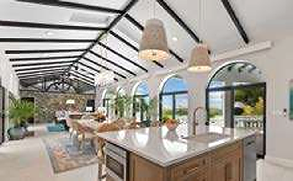 Villa chef kitchen with vaulted beamed ceilings and arched ocean-view windows