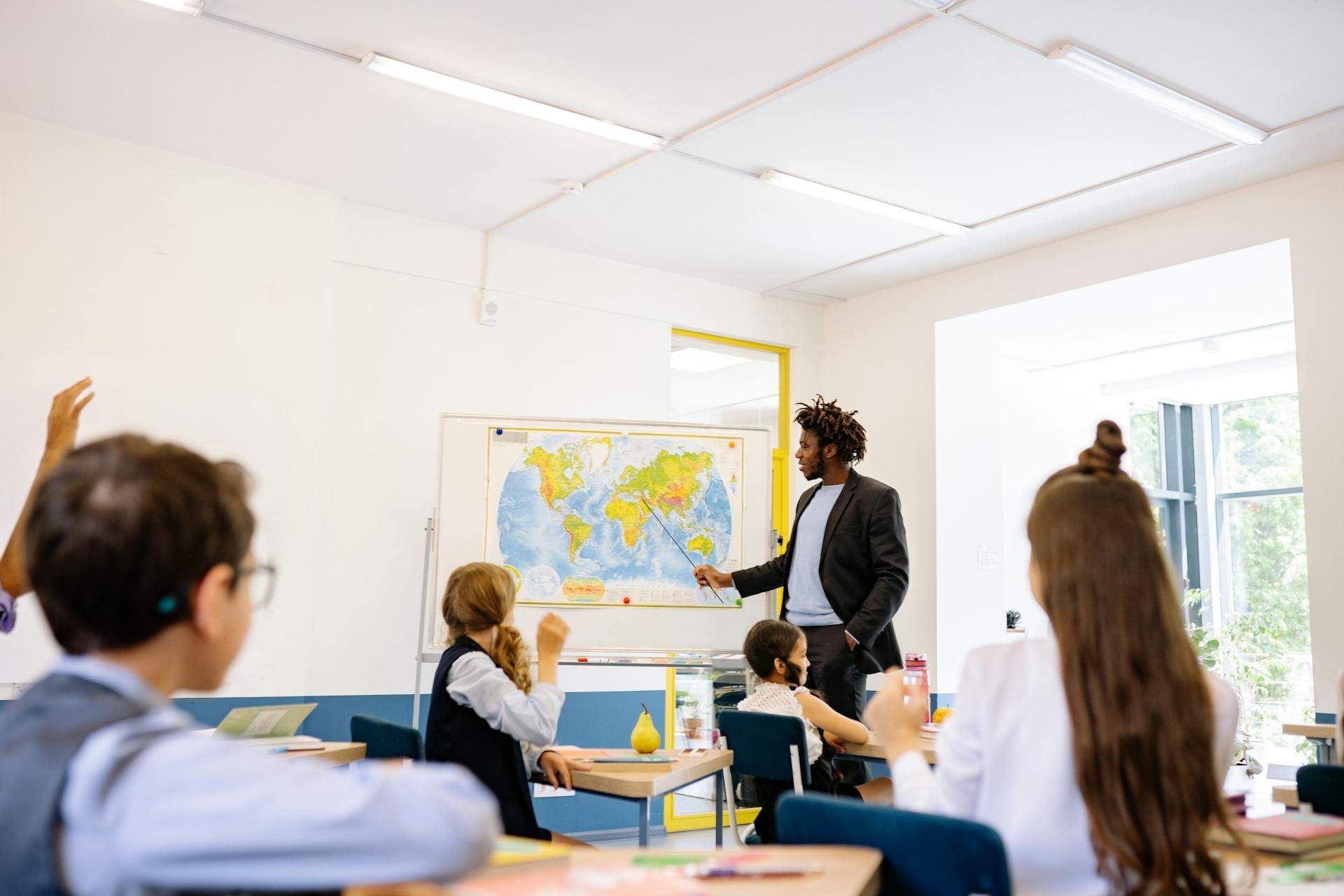 Teacher pointing at world map with students