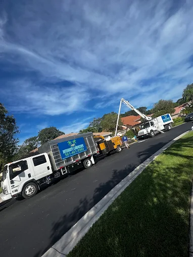 Two Integrity Landscape branded trucks and a bucket crane truck lined up on a residential street ready for a tree service job