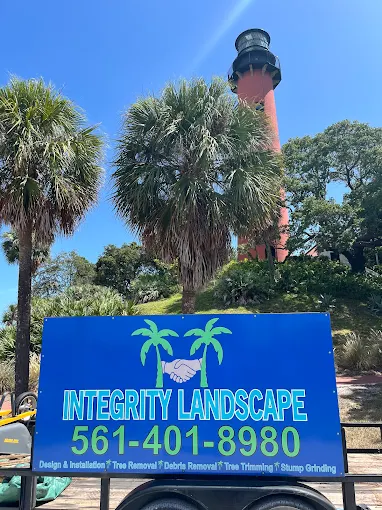 Integrity Landscape branded trailer sign with company name and phone number in front of the historic Jupiter Lighthouse in Palm Beach County