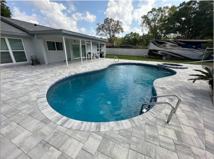 Custom kidney-shaped pool with gray paver pool deck surround installed by Integrity Landscape