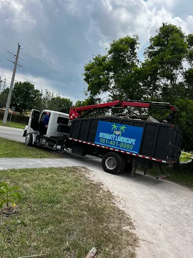 Integrity Landscape branded black dump truck with crane arm used for debris hauling after tree service