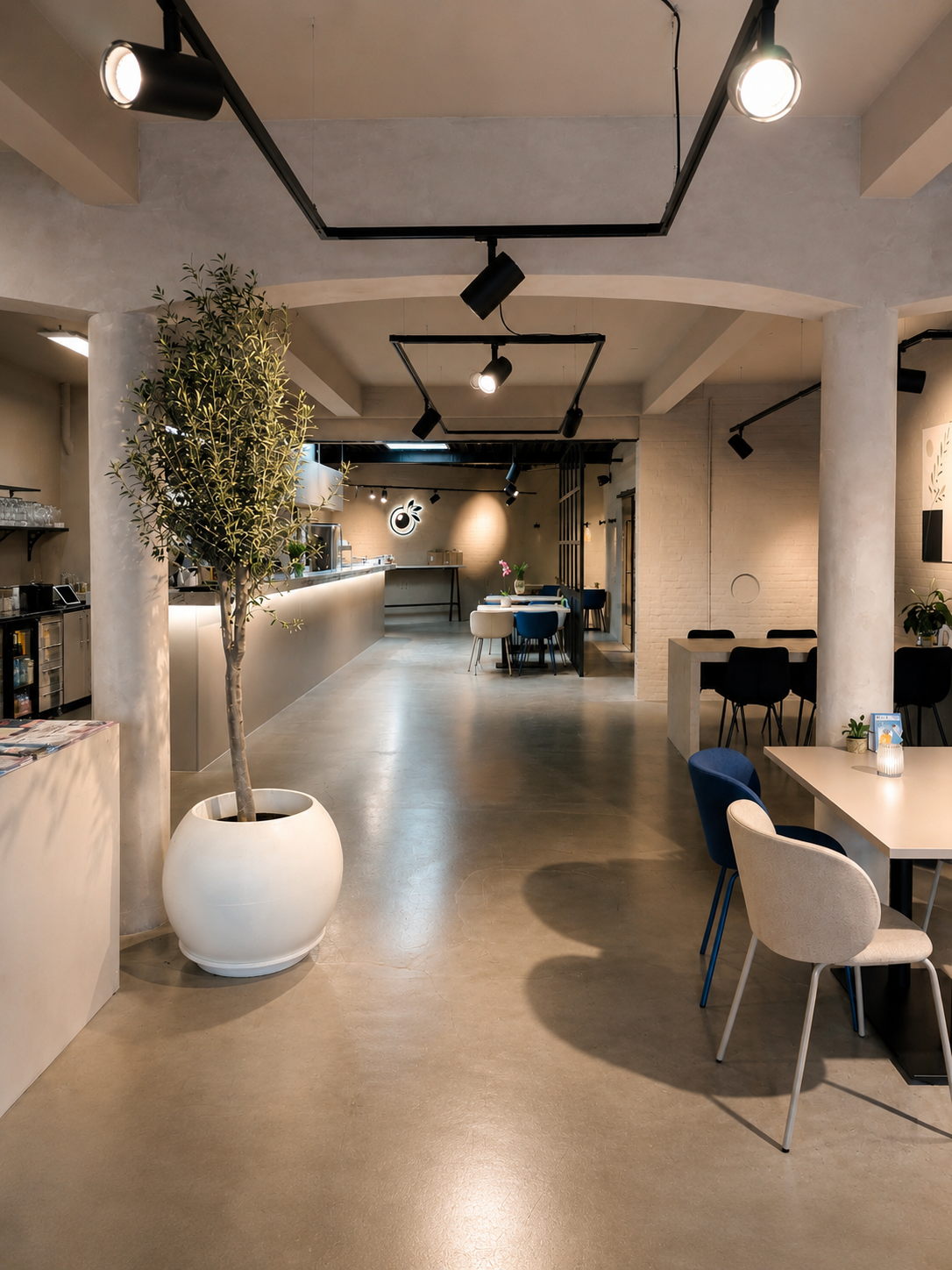 Restaurant interior with olive tree and open-concept kitchen