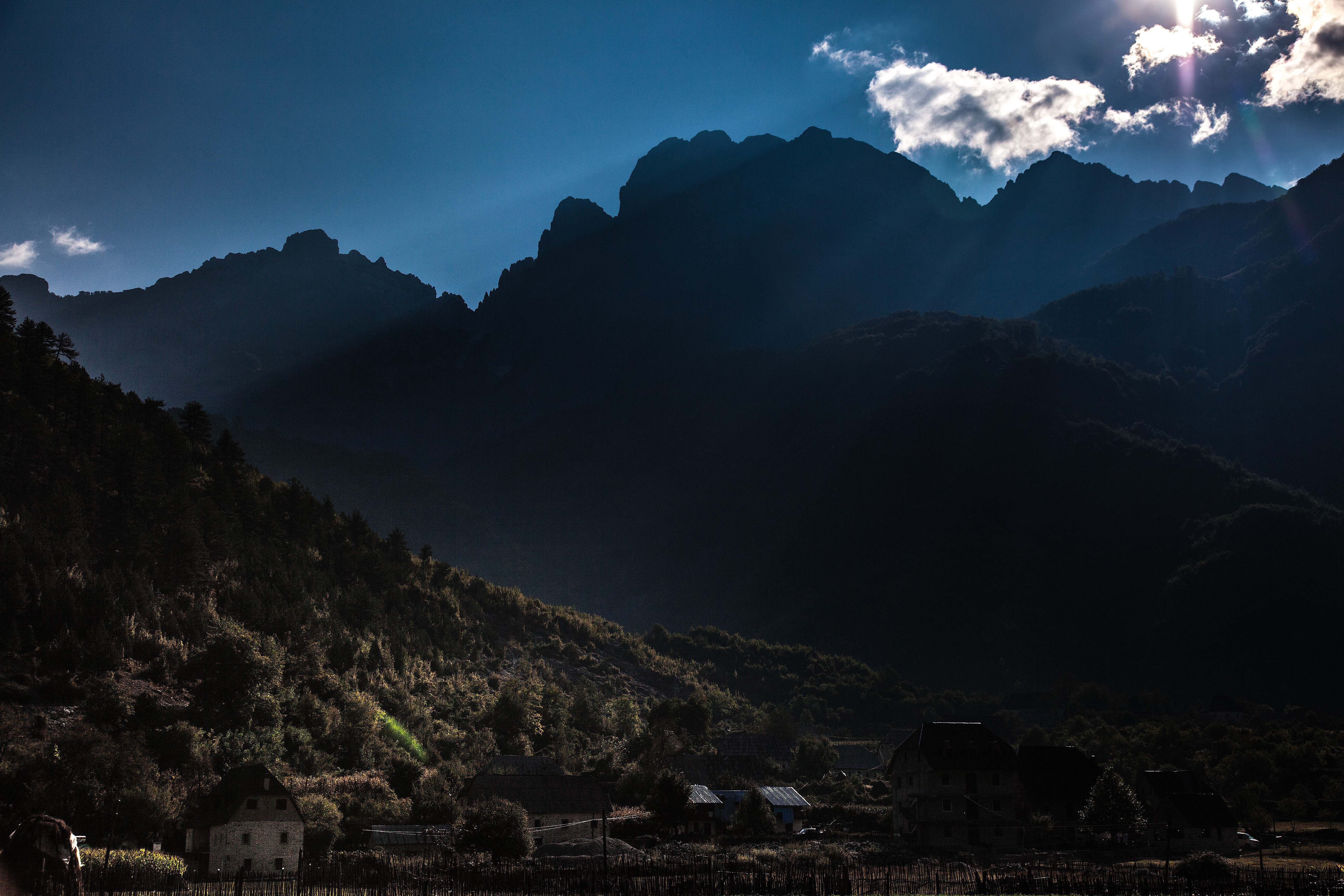 Theth valley beneath layered mountain peaks and dramatic clouds