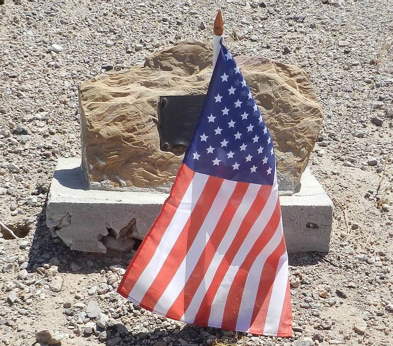John Harger's dark grave marker behind an American flag at Holly Cemetery