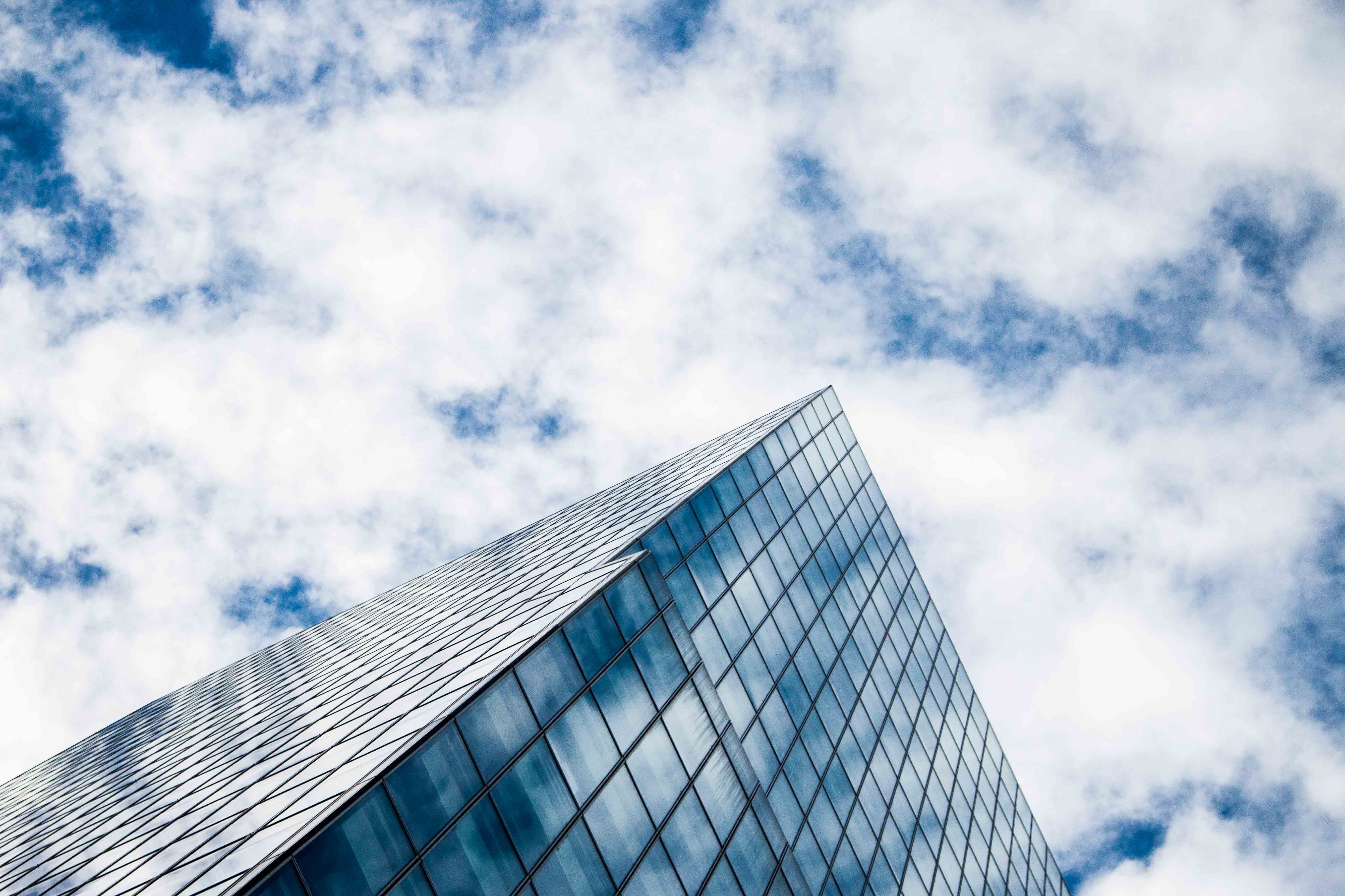 Modern glass skyscraper against blue cloudy sky