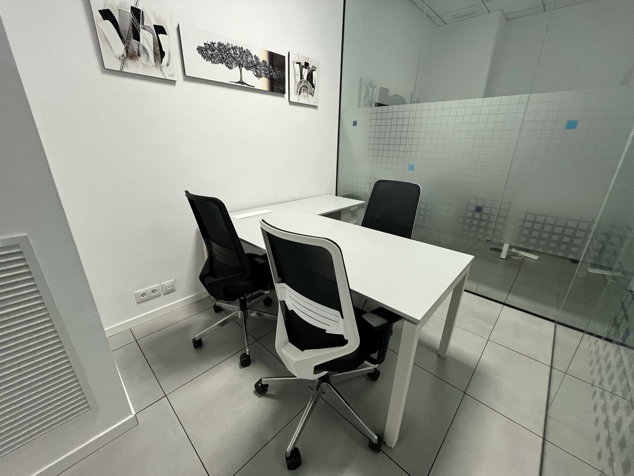 Oficina privada Júpiter con mesa y sillas junto a una pared de cristal