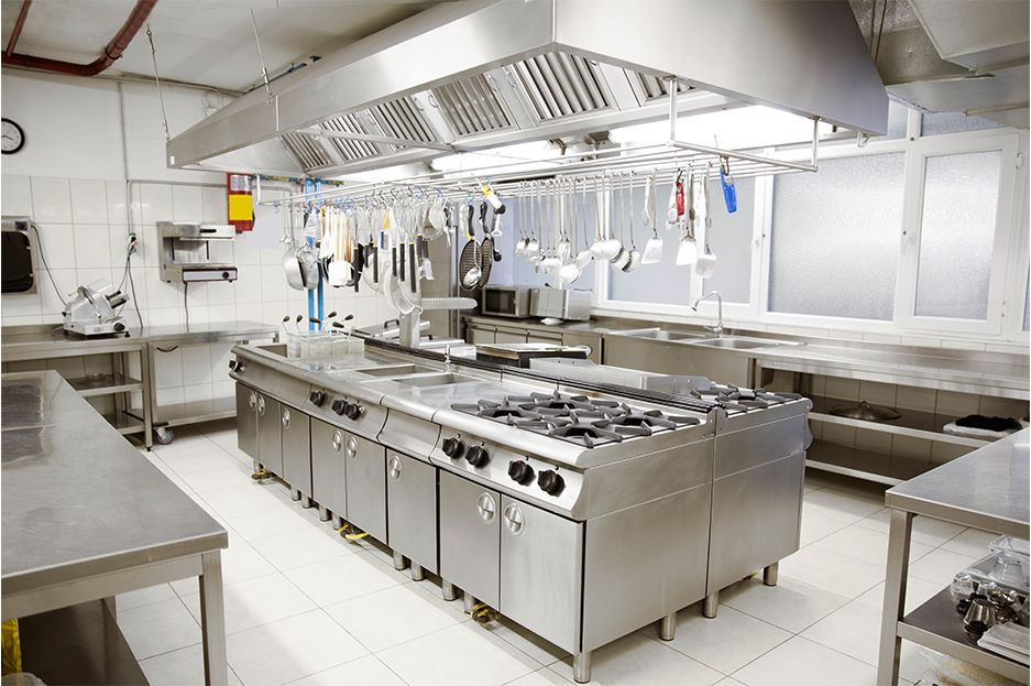 Professional stainless steel commercial kitchen with gas ranges and extraction hoods