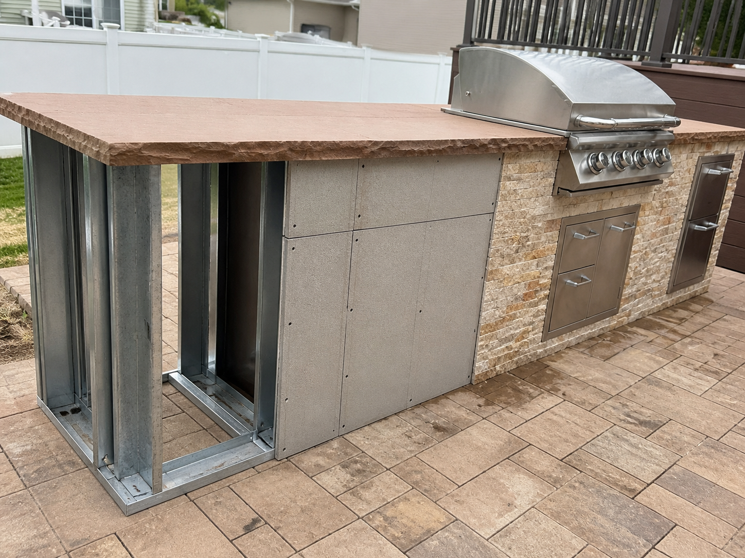 Outdoor kitchen construction showing steel framing, cement board sheathing, and stone veneer finish