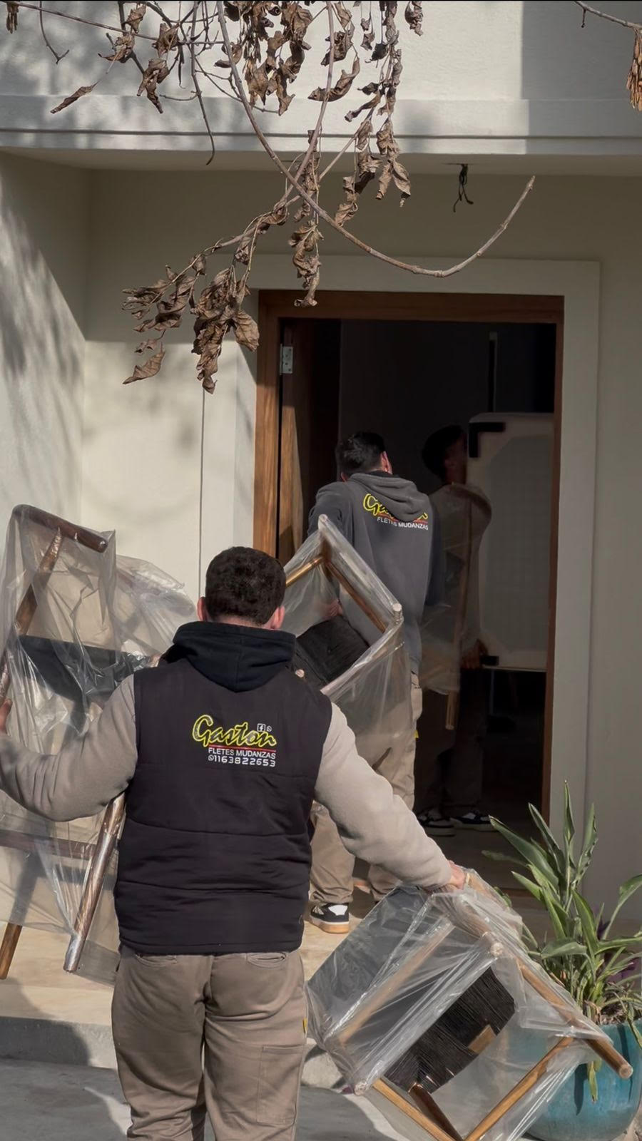 Equipo Gastón transportando sillas envueltas en plástico a una casa moderna